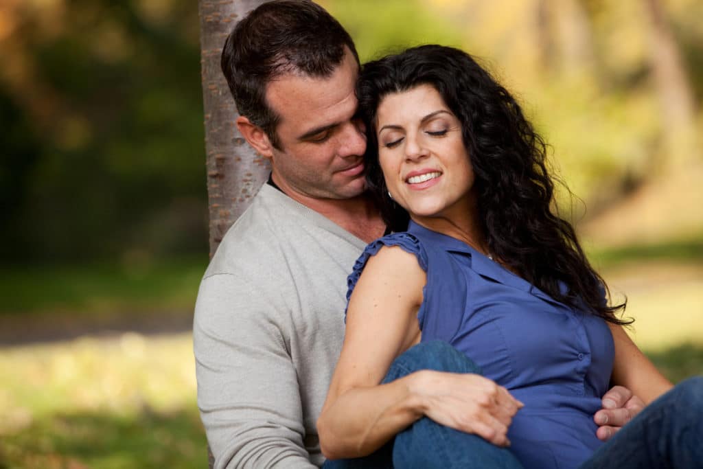 A man and woman hugging in a park.