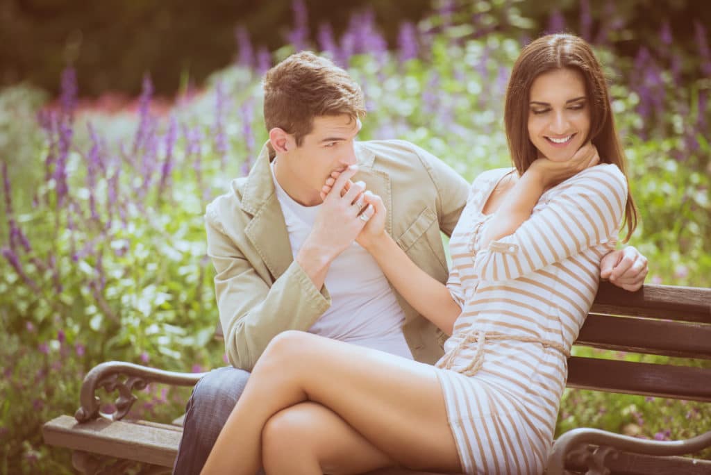 A man and woman sitting on a bench in a park.