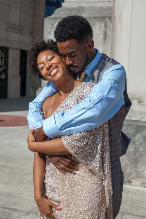 A man and woman hugging in front of a building.