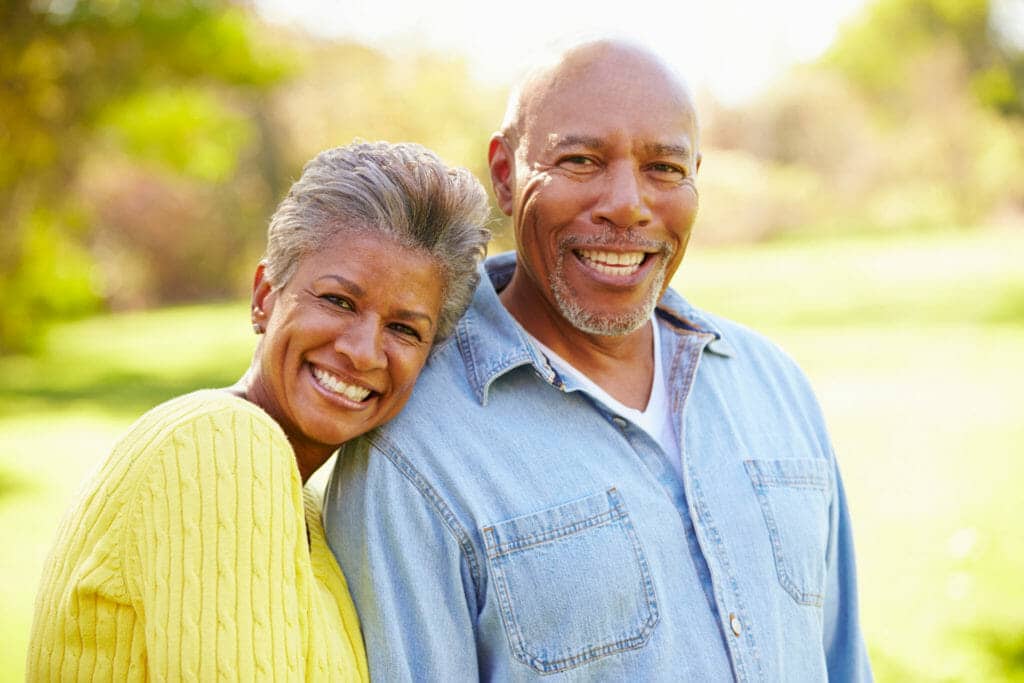 An older couple smiling in a park.