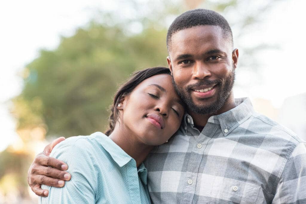 A black man and woman hugging in the street.