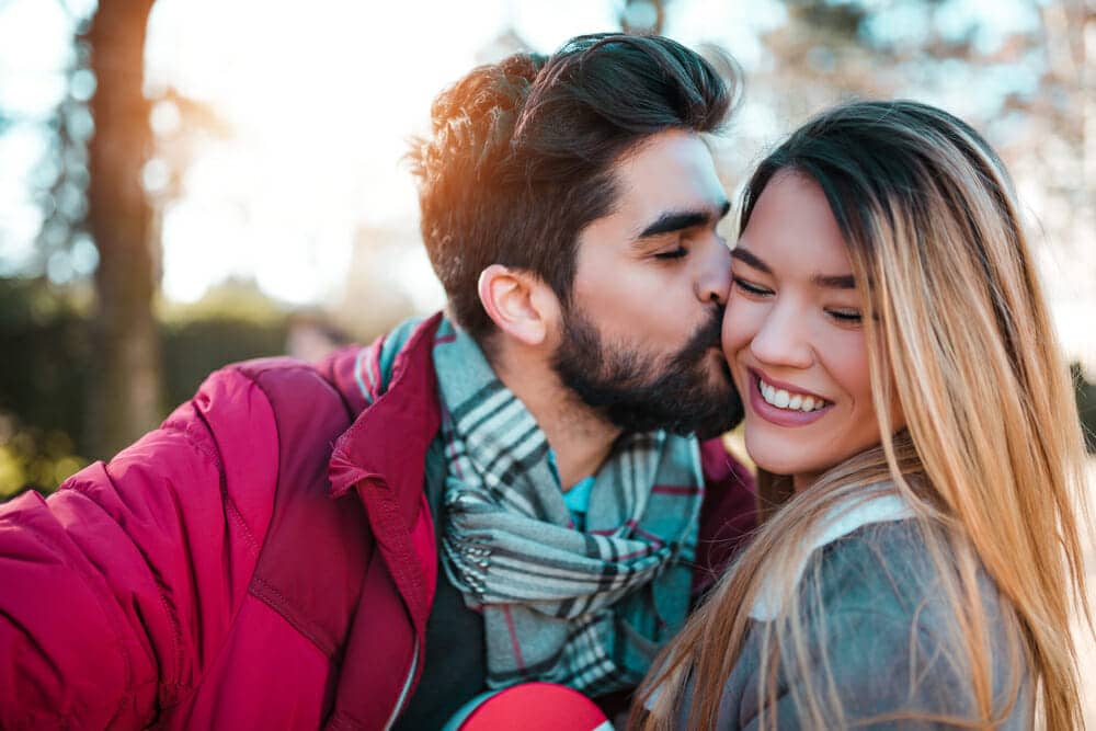 A man and woman are taking a selfie in a park.