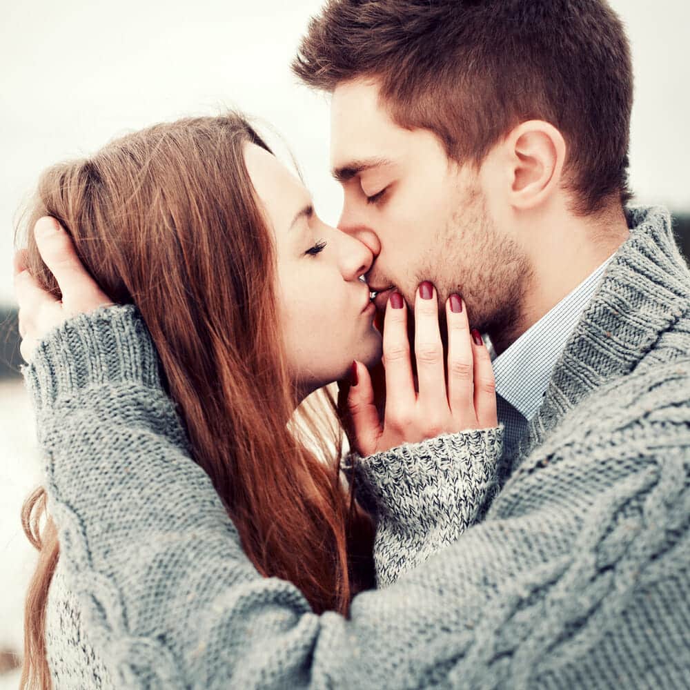 A man and woman kissing in the snow.