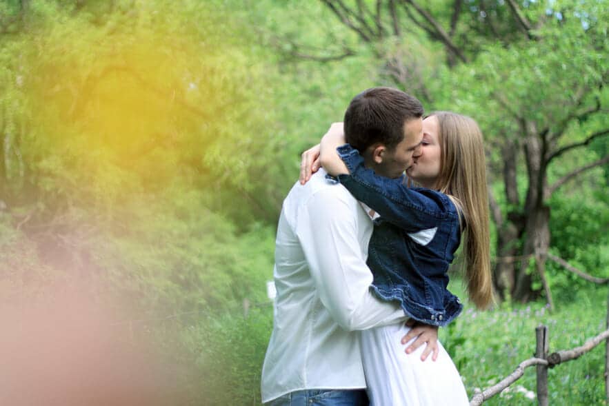 A man and woman kissing in a park.