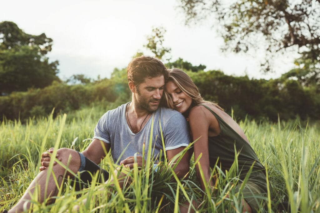 A man and woman sitting in tall grass.