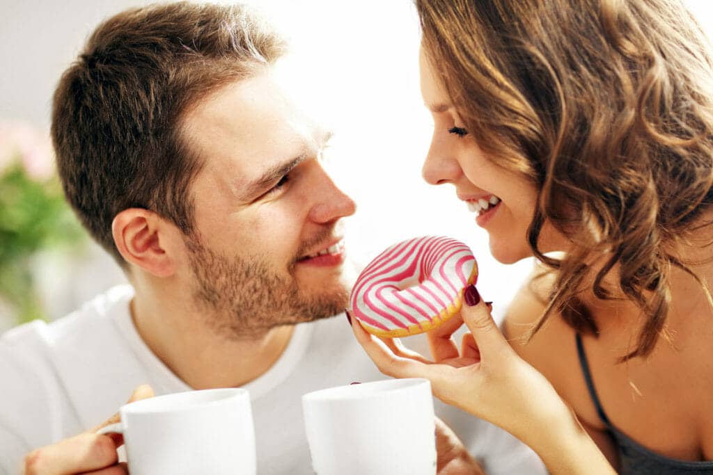 A man and a woman eating a donut.