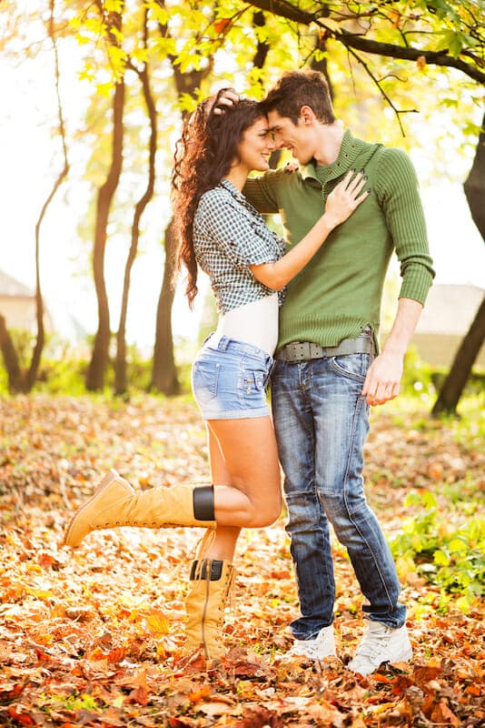 A young couple embracing in the autumn leaves.