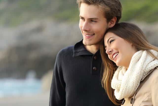 A man and a woman standing on the beach.