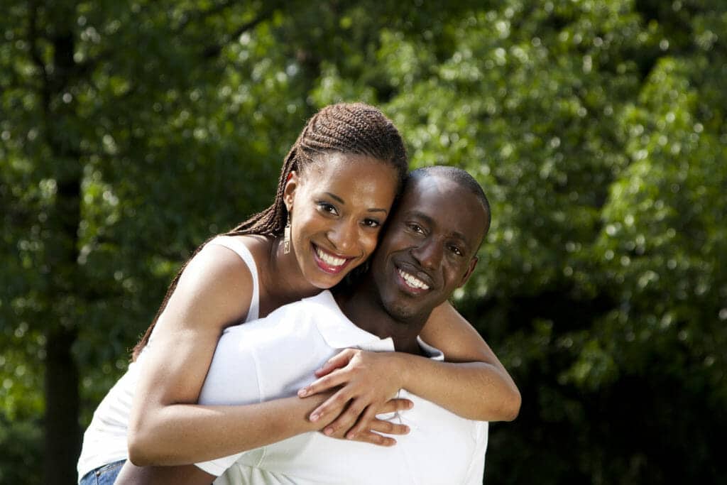 A black man and woman hugging each other in a park.