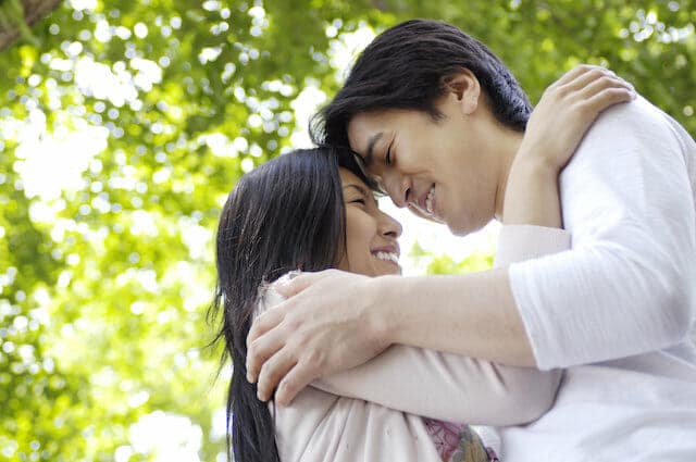 A man and woman hugging in a park.