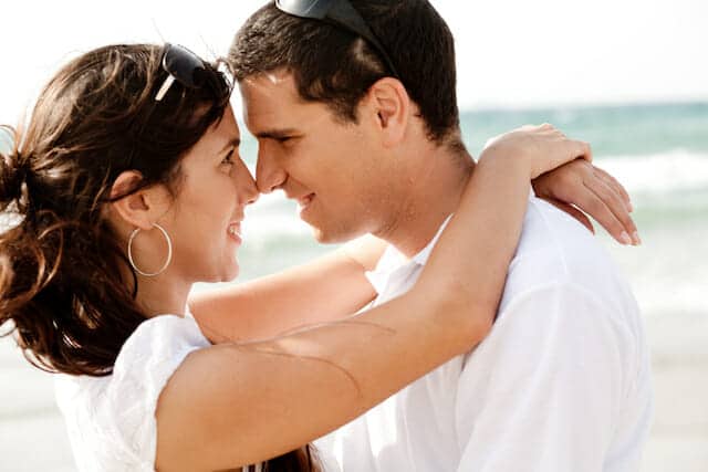 A man and woman hugging on the beach.