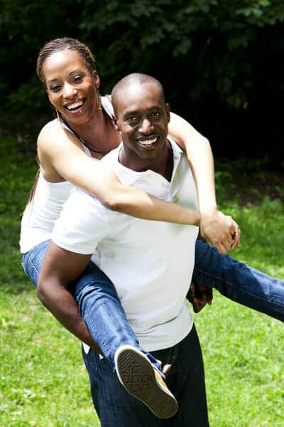 A man is carrying a woman in the park.