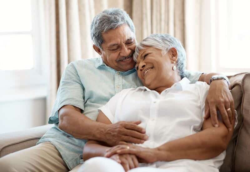 An older couple hugging on a couch.