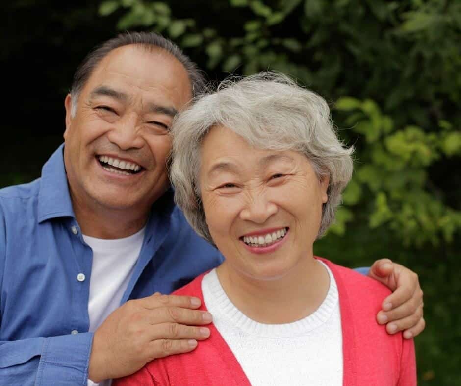 A smiling asian couple posing for a photo.