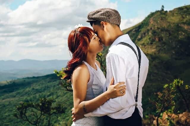 A man and woman kissing in the mountains.