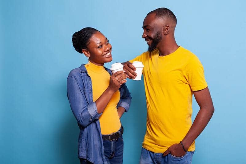 A man and a woman drinking coffee on a blue background.