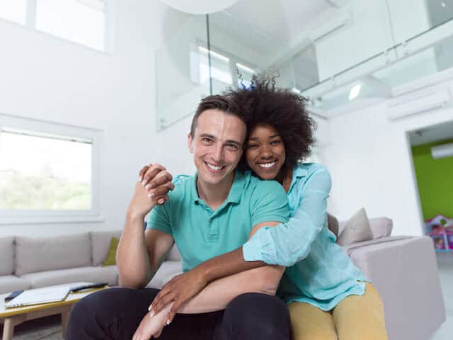 A young couple sitting on the couch in their new home.