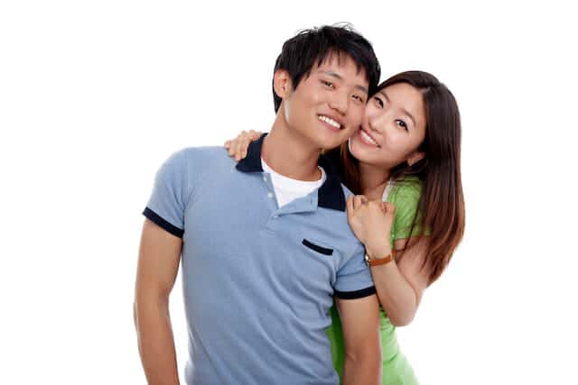 A young couple embracing each other on a white background.