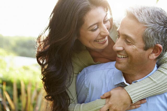 A man and woman hugging each other in a garden.