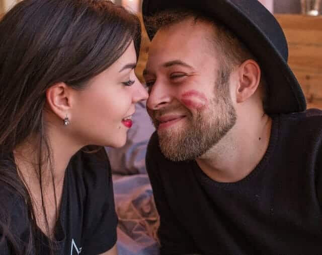 A man and a woman kissing on the cheek.