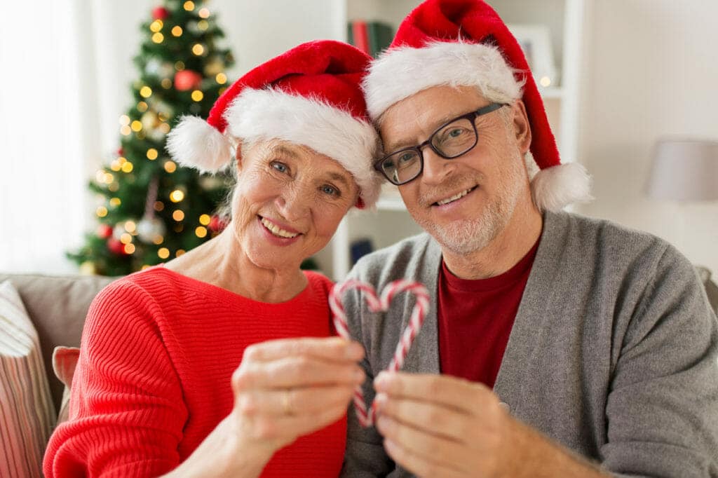 A couple in santa hats holding candy canes.