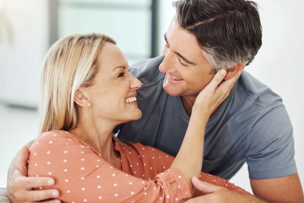 A man and woman hugging while sitting on the couch.