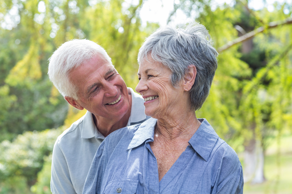 An older couple smiling in a park.