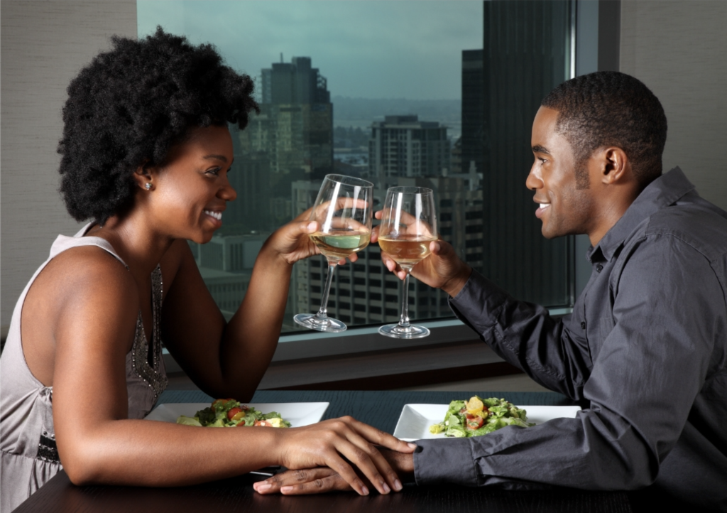 A man and woman toasting glasses of wine at a restaurant.