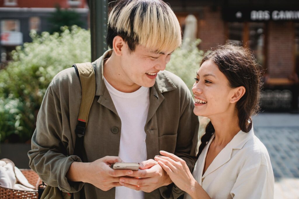 A man and woman are looking at a cell phone.