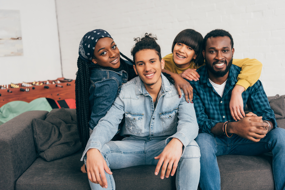 A group of friends sitting on a couch in a living room.