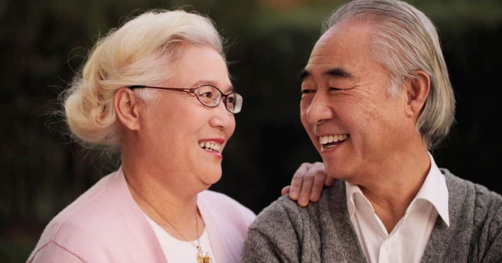 An older couple smiling together in a park.