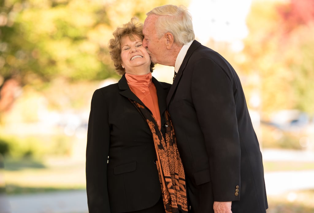 An older couple kissing in the park.