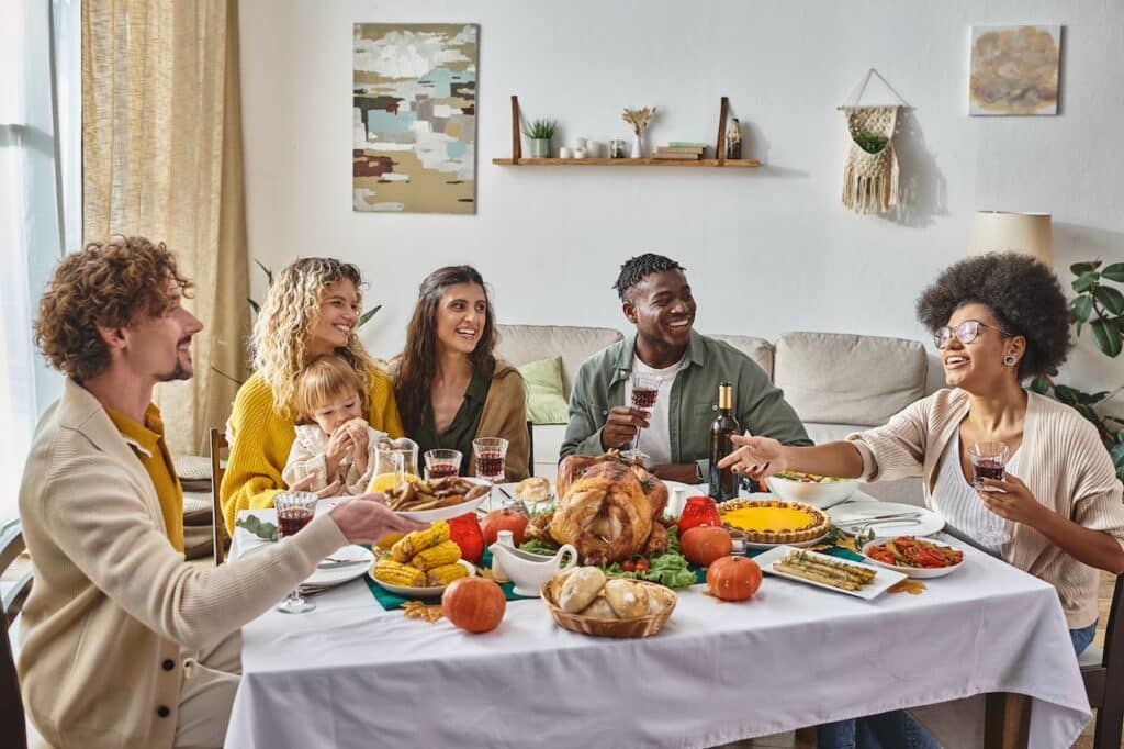 A group of people sitting around a table eating thanksgiving dinner.