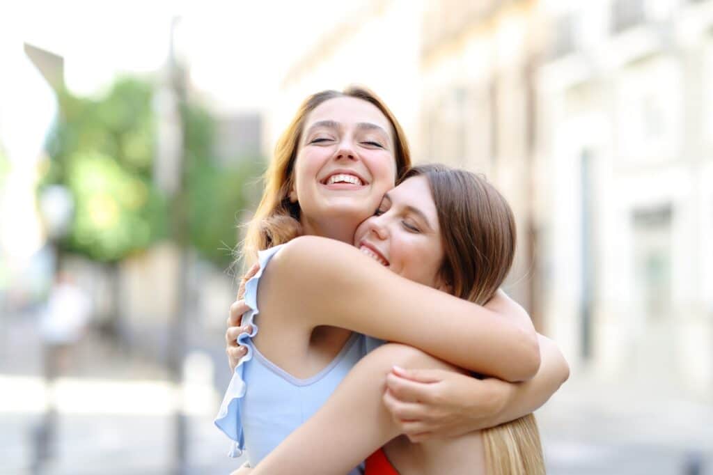 Two women hugging each other on the street.